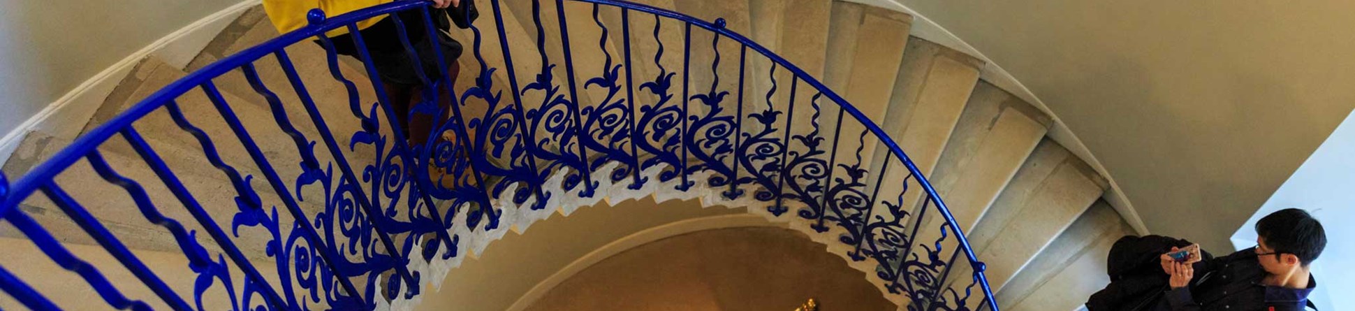 Two people standing on a metal spiral staircase.