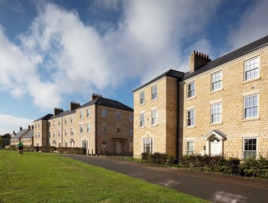 A group of larger three-storey modern houses with stone exteriors, built in an adaption of Georgian style.