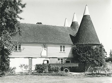 Wooden slated building with roundels at one end. A truck is parked outside