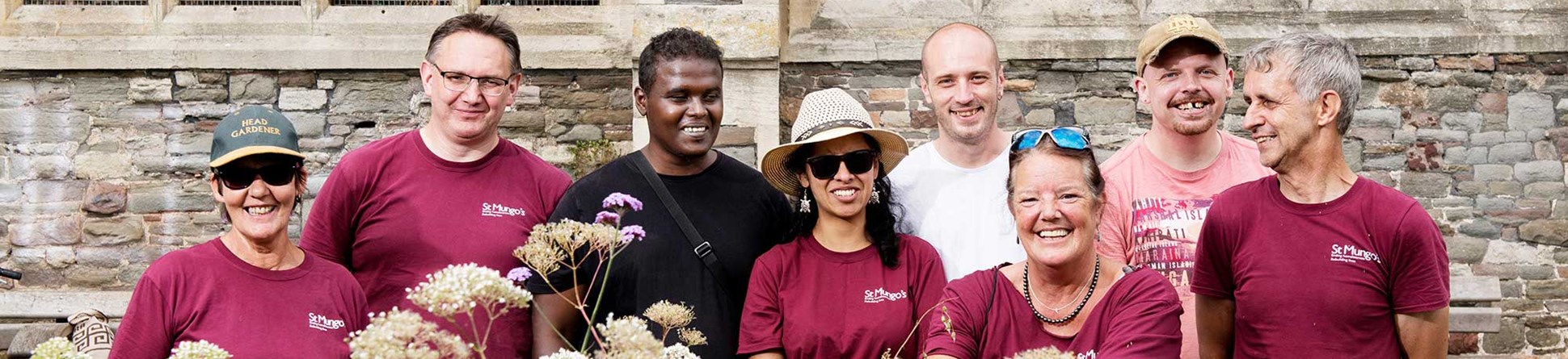 Group of people standing in front of church building with plants in front of them