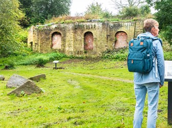 Extreior, general view with visitor reading signage in front of lime kilns. View from north.