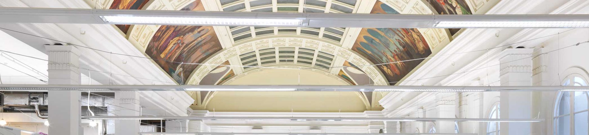 People working in an IT office with an elaborate historic ceiling.