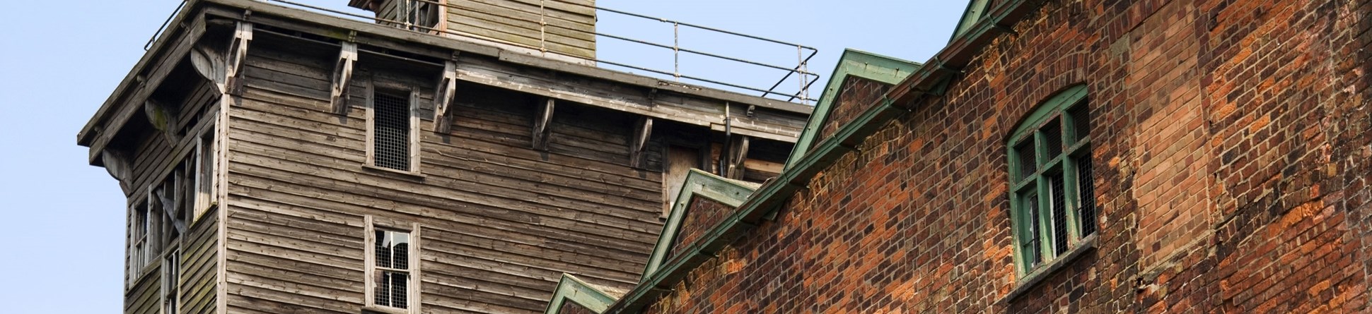 Exterior view of looking up at red brick industrial building with a wooden turret on top.