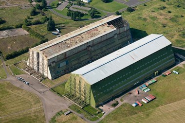 Cardington Royal Airship Works, Bedfordshire. The Royal Airship Works at Cardington manufactured airships in the First World War. To the right is the original structure where the work was carried out. Today the site is still in use for the construction of modern airships. The airship shed to the left was moved from Pulham, Norfolk to this site in 1928