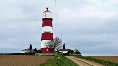 Grass in foreground in red and white lighthouse in background