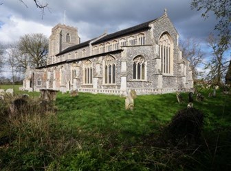 Church built of rubble with flint dressing, showing plain glass traceried windows and square tower.