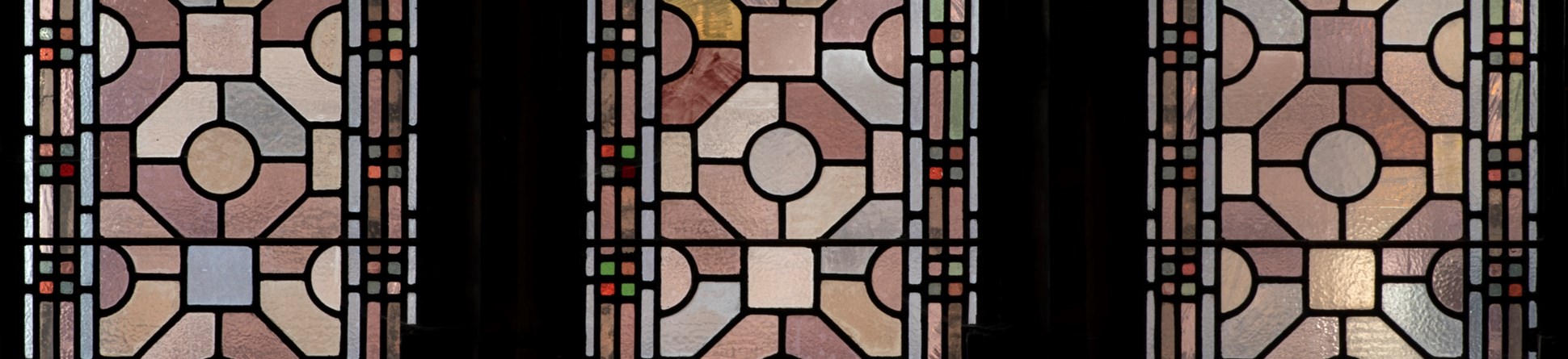 the photograph shows geometric stained glass in muted colours.