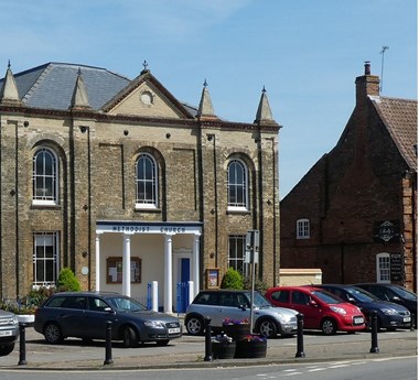 Old brick building behind a line of parked cars.