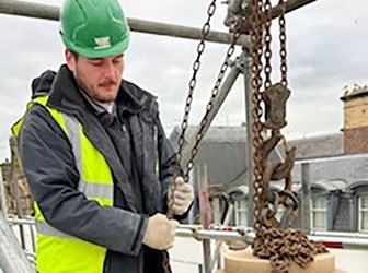 Apprentice Matthew Tinsley manipulates a chain winch to move a masonry feature. 