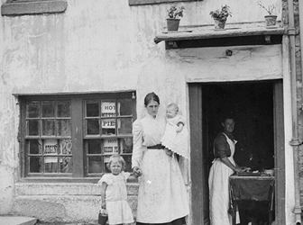 A black and white photograph of a woman and children outside of a Pie Shop.