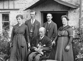 A black and white photograph of a family posed outside a house.
