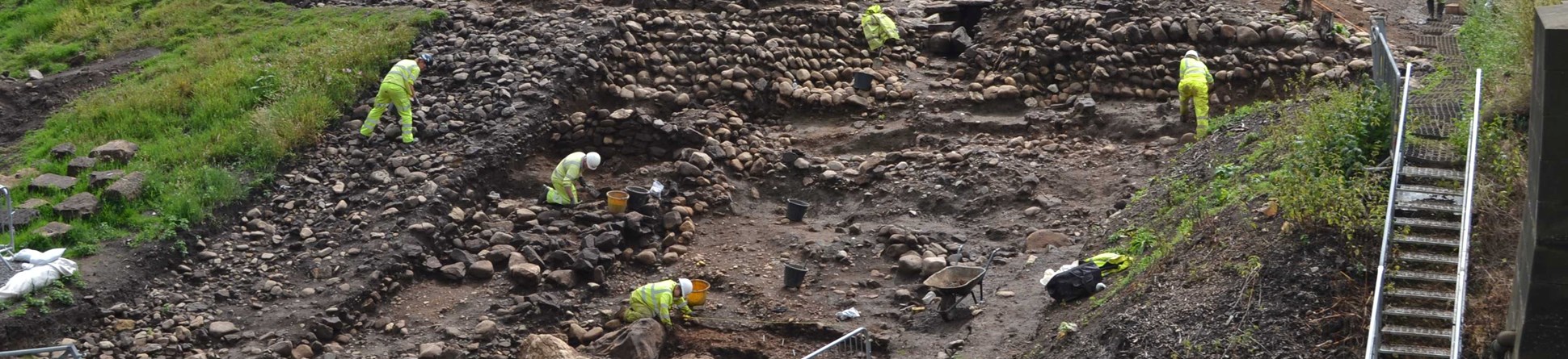 Image of archaeologists excavating Roman revetments, built to protect the river shore from erosion. This excavation was carried out in 2014, East of A1 on the south side of the River Swale near Catterick. 