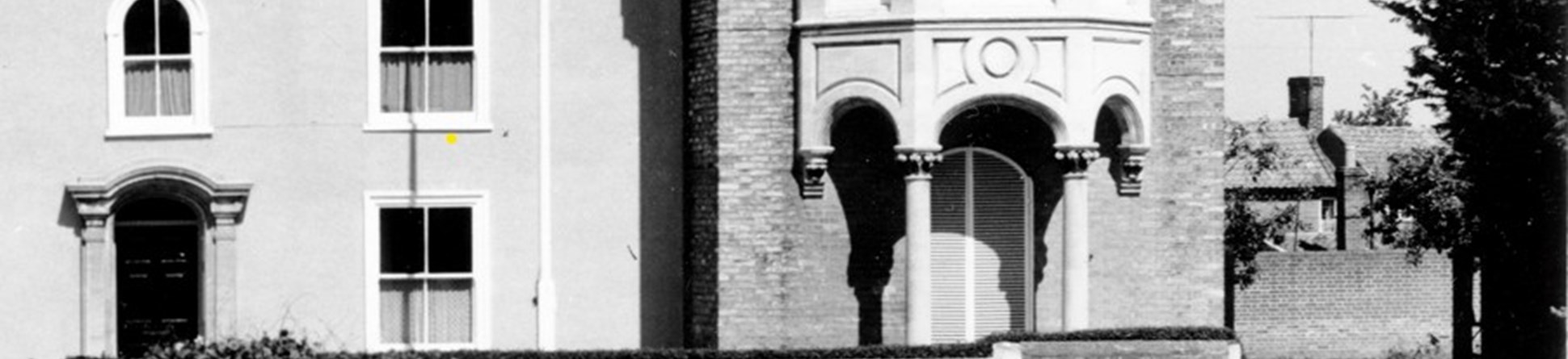 A black and white photo of The Cedars shows a two storey brick building with pillared doorway, and a sculptured bay window with pillars on a projected storey to the right.