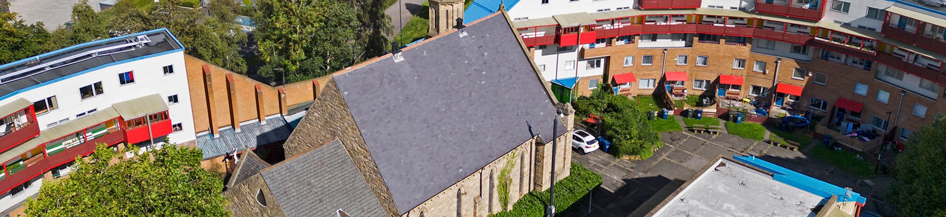 Exterior, drone image from west showing church, snaking estate buildings.